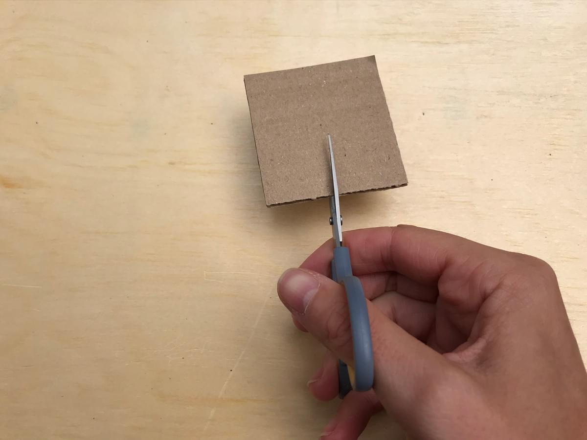 hand holding scissors, cutting in to the cardboard hand holding scissors, cutting in to the cardboard