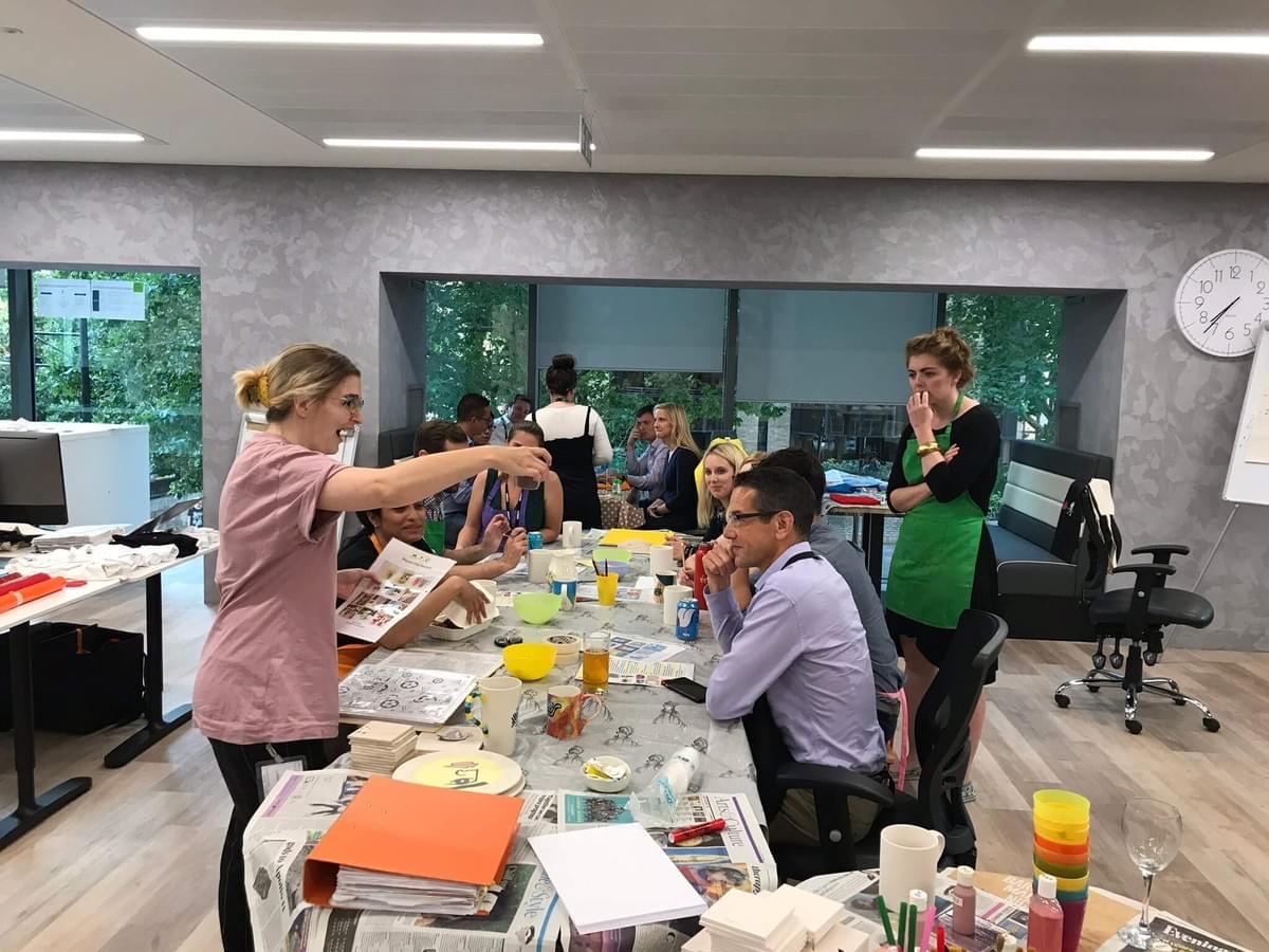 A group of Slalom employees say a table, being taught ceramic painting A group of Slalom employees say a table, being taught ceramic painting