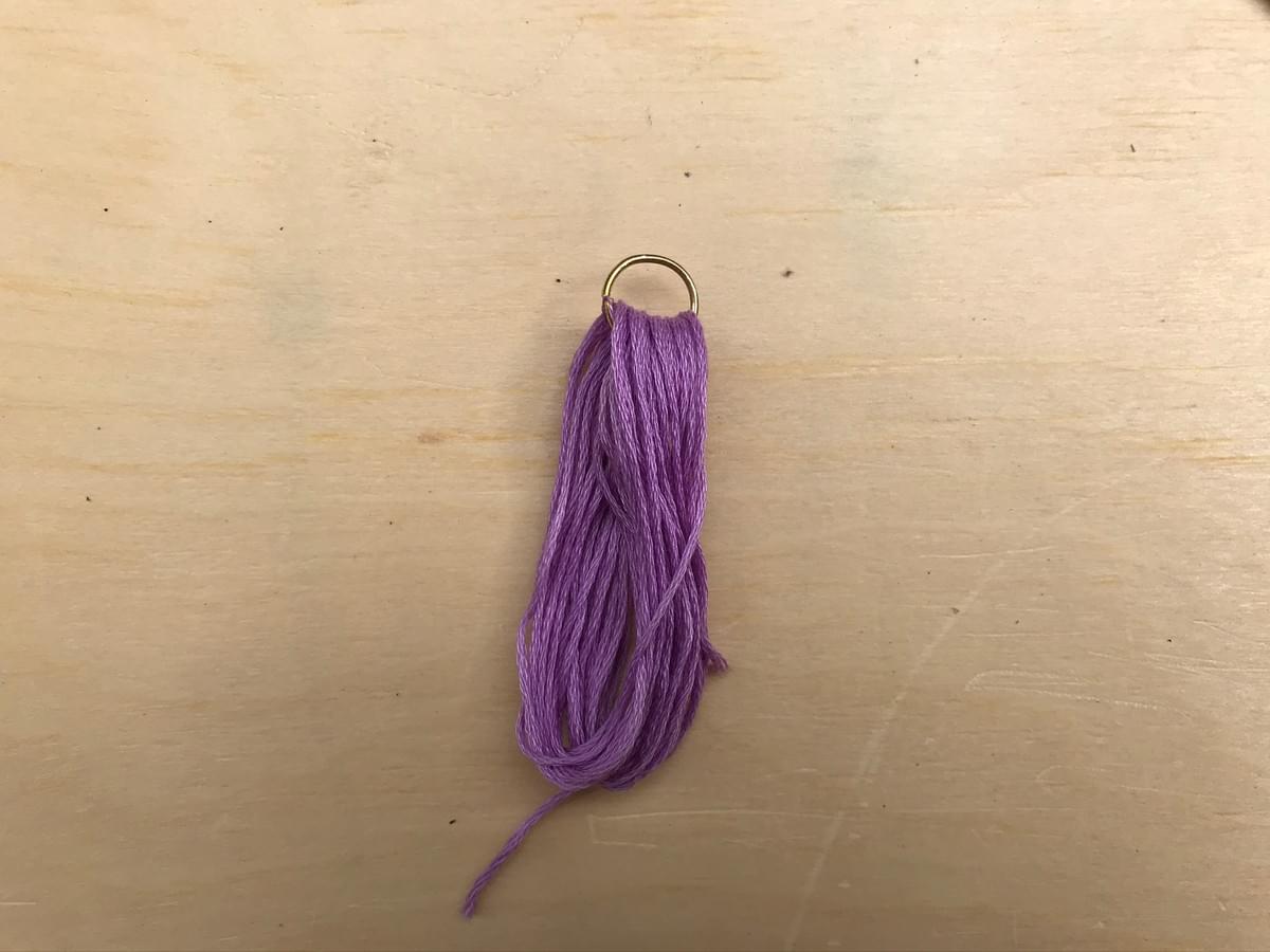 The thread and hoop now removed from the card and lay on the table The thread and hoop now removed from the card and lay on the table