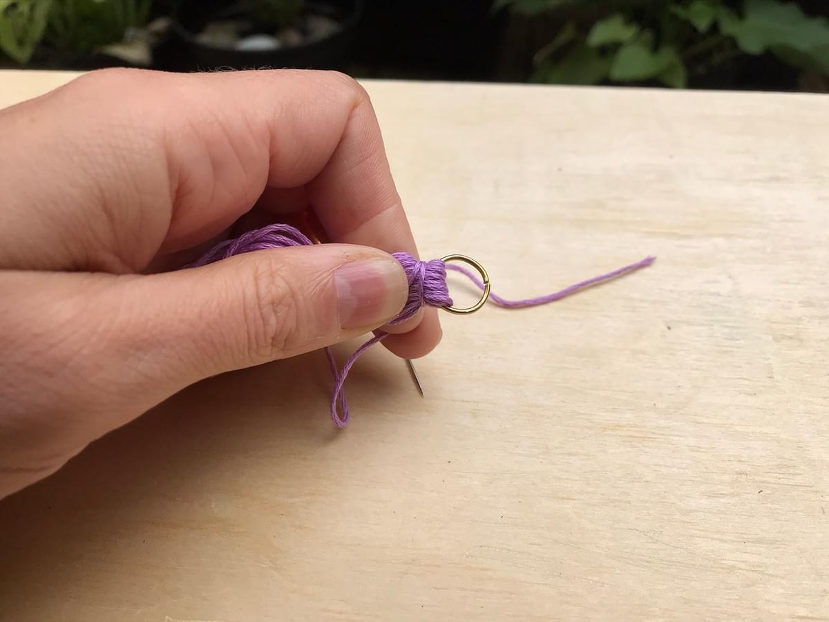Hand holding the thread near the ring at the tip, the short thread is beginning to be wound round Hand holding the thread near the ring at the tip, the short thread is beginning to be wound round