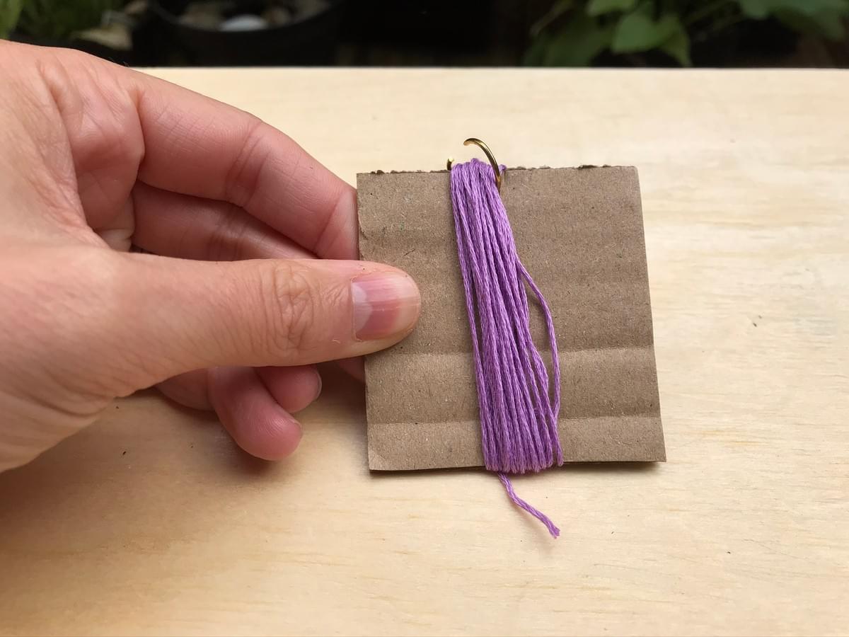 Hand holding card, showing thread wrapped around the card, through the gap in the ring Hand holding card, showing thread wrapped around the card, through the gap in the ring