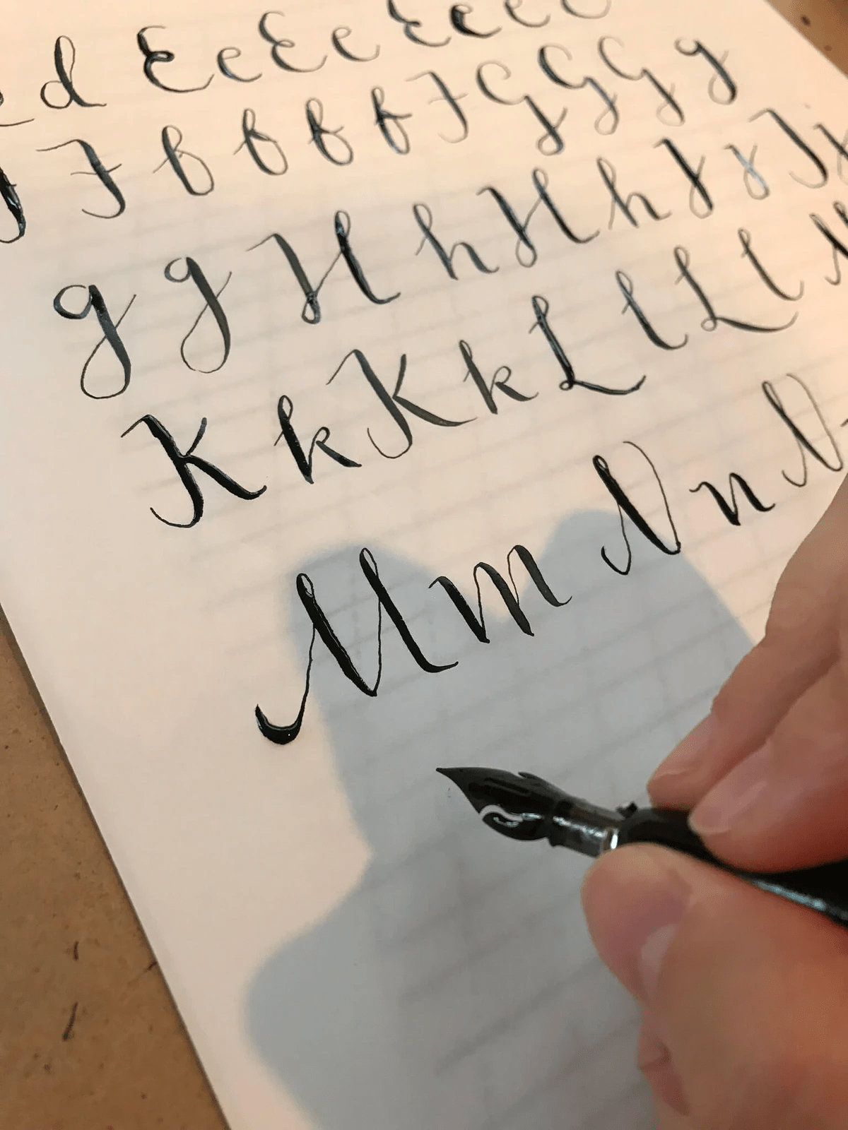 Close up of hand holding a calligraphy pen, writing out the alphabet Close up of hand holding a calligraphy pen, writing out the alphabet