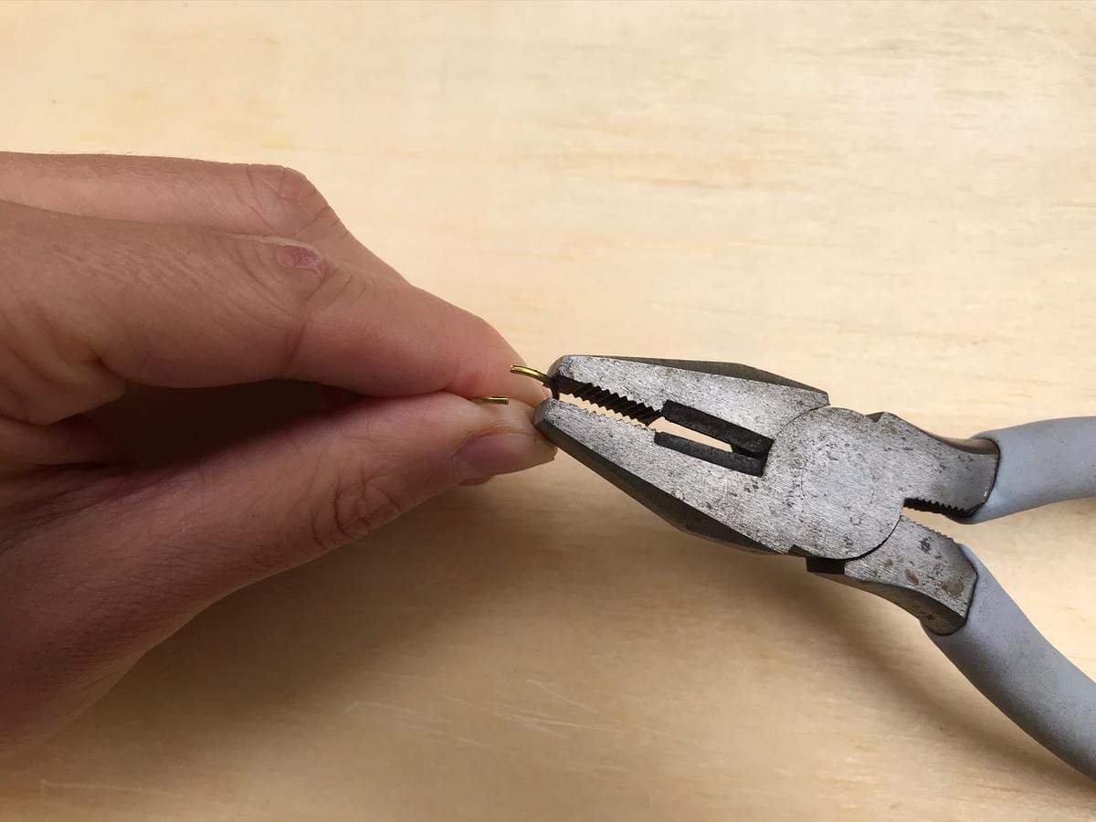 hand holding the ring, pliers prising it open hand holding the ring, pliers prising it open