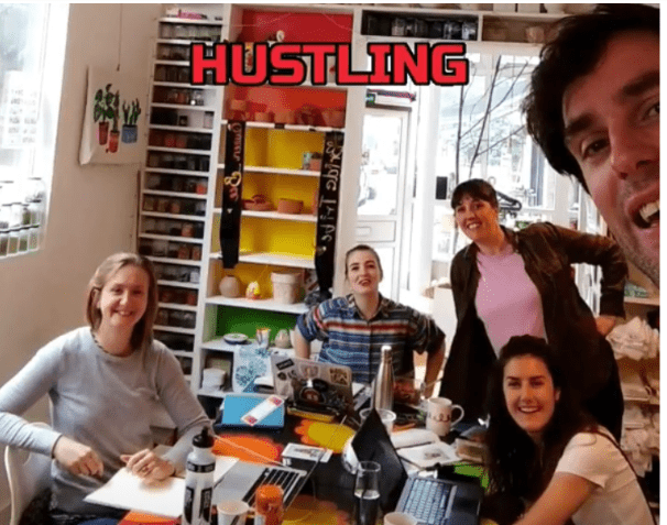 M.Y.O team on team hustle day sat around a table, smiling at the camera M.Y.O team on team hustle day sat around a table, smiling at the camera