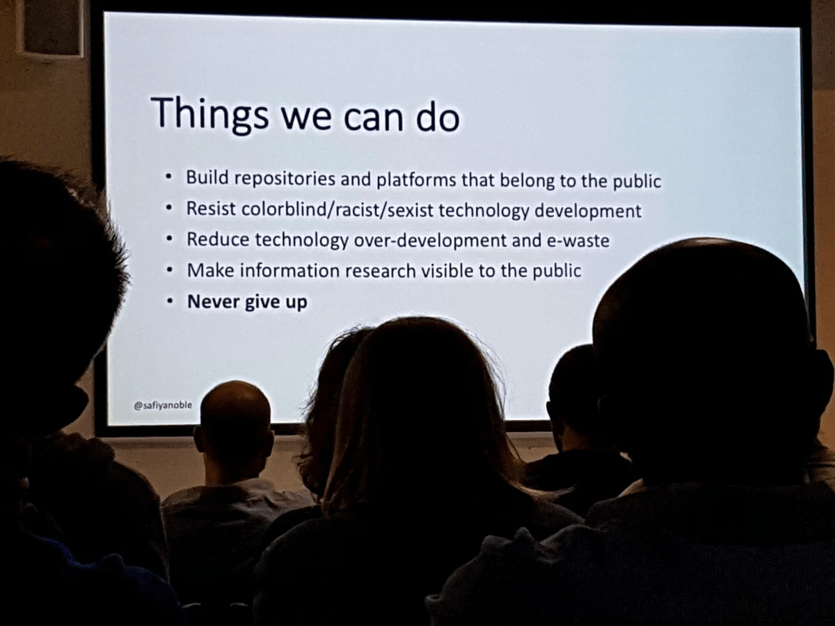 A slide titled "Things we can do" presented on a screen in front of a group of people in silhouette . The bullet points read: 1) Build repositories and platforms that belong to the public. 2) Resist colorblind, racist, sexist technology development. 3? Reduce technology over-development and e-waste. 4) Make information research visible to the public. 5) Never give up. A slide titled "Things we can do" presented on a screen in front of a group of people in silhouette . The bullet points read: 1) Build repositories and platforms that belong to the public. 2) Resist colorblind, racist, sexist technology development. 3? Reduce technology over-development and e-waste. 4) Make information research visible to the public. 5) Never give up.
