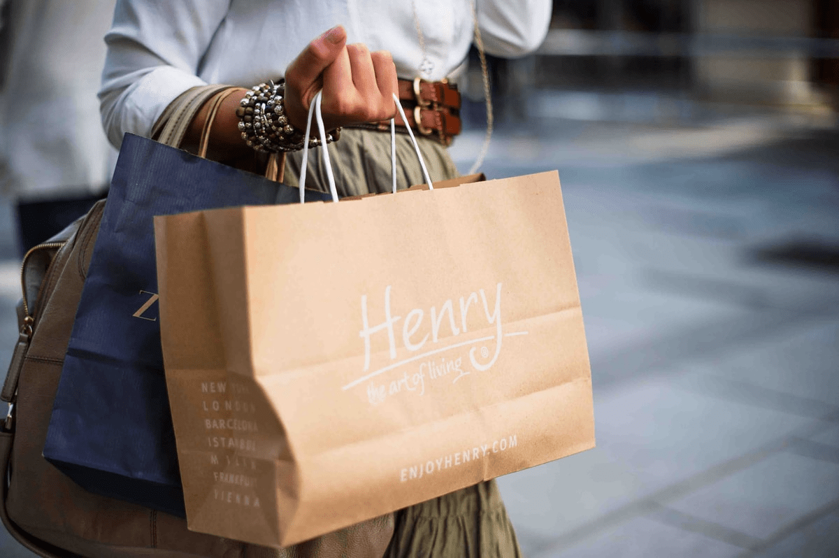 person holding brown shopping bag that says henry, holiday shopping, ad campaign, facebook ads person holding brown shopping bag that says henry, holiday shopping, ad campaign, facebook ads