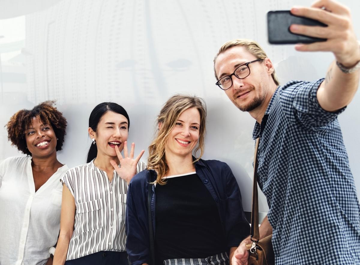 guy taking a selfie with three female coworkers to create interesting and entertaining content for Instagram guy taking a selfie with three female coworkers to create interesting and entertaining content for Instagram