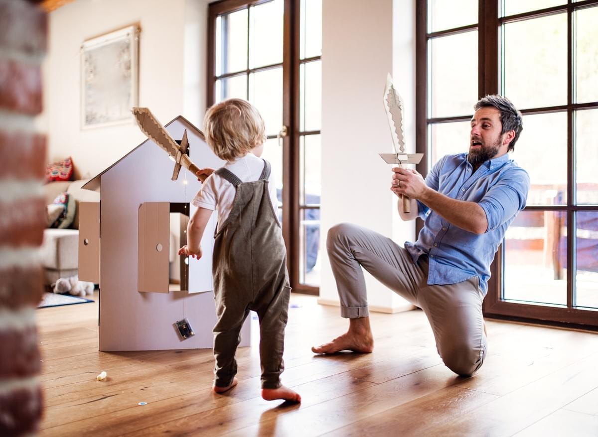 Un père et son petit garçon jouant à l'intérieur avec des épées en bois, papa, enfant, confinement, jeu Un père et son petit garçon jouant à l'intérieur avec des épées en bois, papa, enfant, confinement, jeu