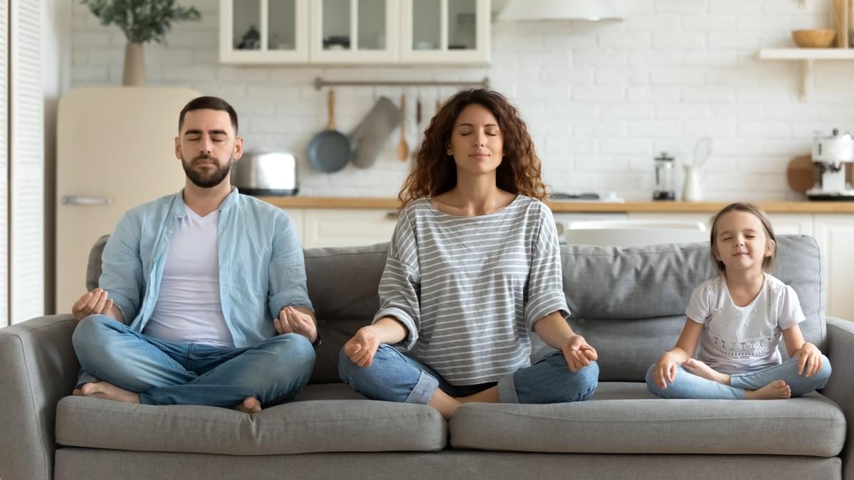 Un homme, une femme et leur fille assis en tailleur sur leur canapé, en pleine séance de méditation. Détente, yoga, relaxation, famille, parent, enfant, maison, confinement, pandémie, coronavirus, en ligne, santé, intérieur, adaptation, bien-être Un homme, une femme et leur fille assis en tailleur sur leur canapé, en pleine séance de méditation. Détente, yoga, relaxation, famille, parent, enfant, maison, confinement, pandémie, coronavirus, en ligne, santé, intérieur, adaptation, bien-être