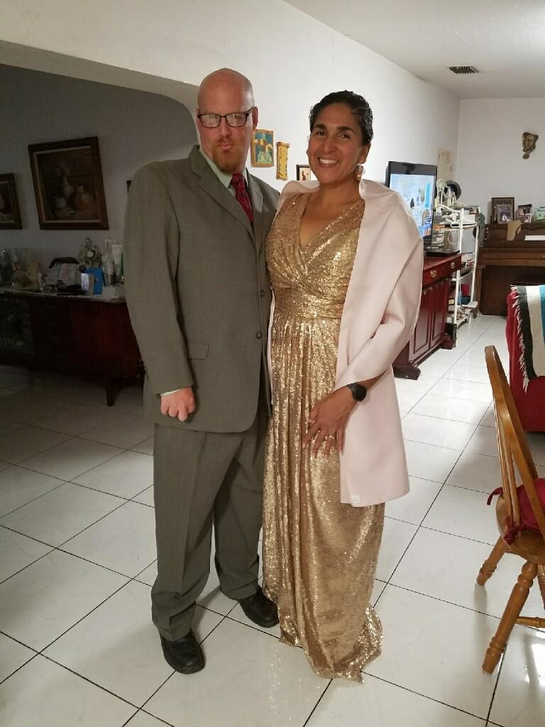 A smiling bald man in a grey suit next to a smiling lady in a gold dress. A smiling bald man in a grey suit next to a smiling lady in a gold dress.