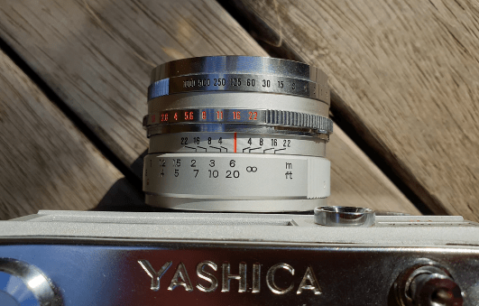 Yashica Ic Lynx 5000E camera from above showing the focus ring, aperture and shutter speed selections on the lens. Yashica Ic Lynx 5000E camera from above showing the focus ring, aperture and shutter speed selections on the lens.