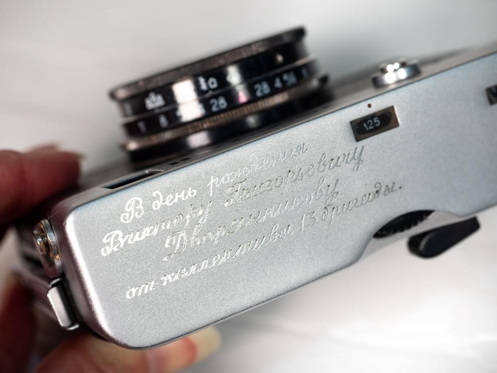 Photograph showing the engraving message on the top of the camera in Russian. Photograph showing the engraving message on the top of the camera in Russian.