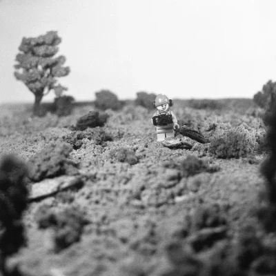 Lego mini figure holding a camera and wearing a hiking backpack in a outdoor scene created with brown sugar and pieces of bark Lego mini figure holding a camera and wearing a hiking backpack in a outdoor scene created with brown sugar and pieces of bark