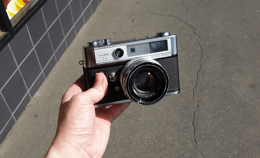 Yashica Ic Lynx 5000E camera held by a hand on a sunny day Yashica Ic Lynx 5000E camera held by a hand on a sunny day