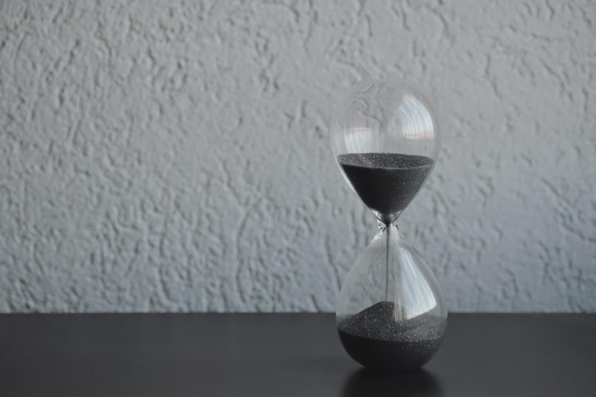 Image of an hourglass on a table representing the concept of time availability when considering a project manager Image of an hourglass on a table representing the concept of time availability when considering a project manager