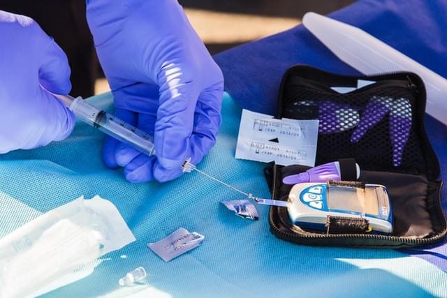 Insulin testing device being operated by gloved hands Insulin testing device being operated by gloved hands