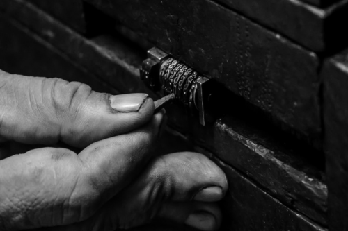 A close up of a hand working on a tiny number lock. A close up of a hand working on a tiny number lock.