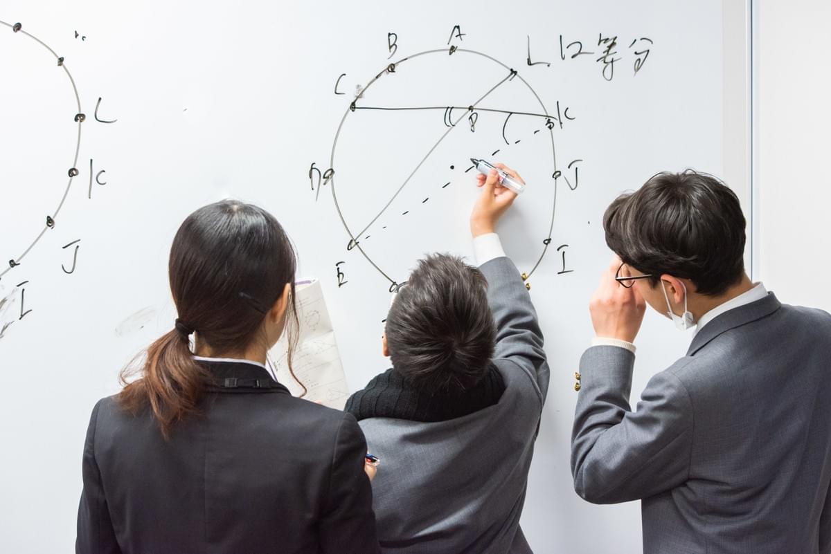 数学の問題を一緒に考える生徒と大学生 数学の問題を一緒に考える生徒と大学生
