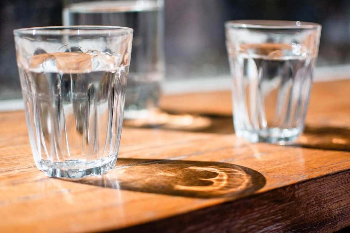 A photo of mostly full glasses of water on a wood table as featured in The Purple Dog Blog by The Purple Dog Vegan A photo of mostly full glasses of water on a wood table as featured in The Purple Dog Blog by The Purple Dog Vegan