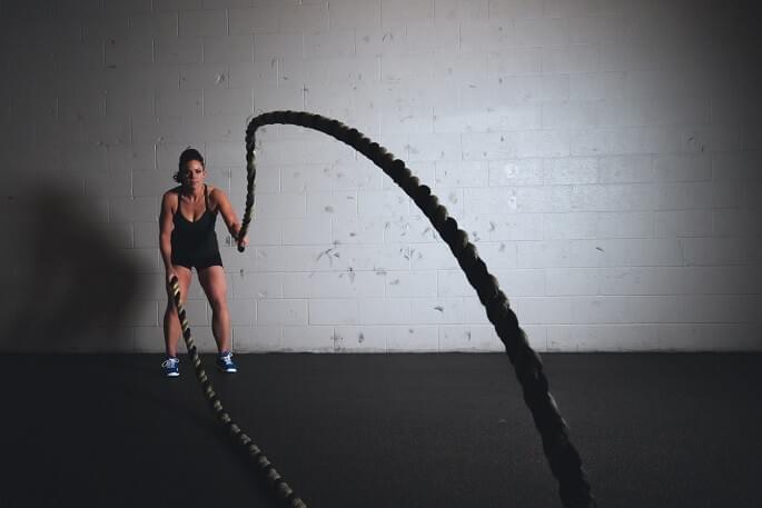 A photo of a woman using battle ropes while exercising during a workout, photo featured in the blog post "A Love Letter to Battle Ropes" by The Purple Dog Vegan A photo of a woman using battle ropes while exercising during a workout, photo featured in the blog post "A Love Letter to Battle Ropes" by The Purple Dog Vegan