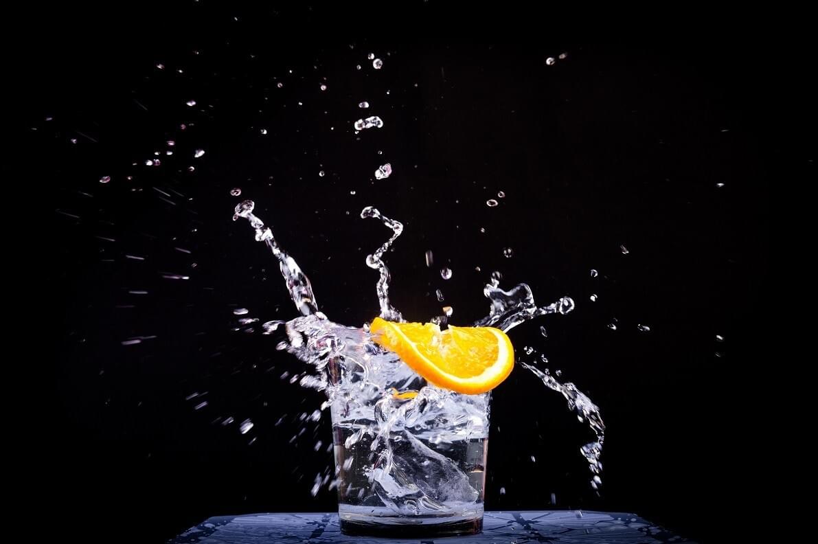 A photo of a slice of orange splashing into a glass of water as featured in The Purple Dog Blog by The Purple Dog Vegan A photo of a slice of orange splashing into a glass of water as featured in The Purple Dog Blog by The Purple Dog Vegan