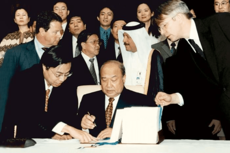 Shi Guangshen, Minister of Foreign Trade and Economic Cooperation of China, signing China's ascension to the WTO in November 2001. Photo courtesy of the WTO. Shi Guangshen, Minister of Foreign Trade and Economic Cooperation of China, signing China's ascension to the WTO in November 2001. Photo courtesy of the WTO.
