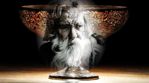 An intricate chalice glows as it is backlit. Within the chalice is the face of and old, beaded man. An intricate chalice glows as it is backlit. Within the chalice is the face of and old, beaded man.