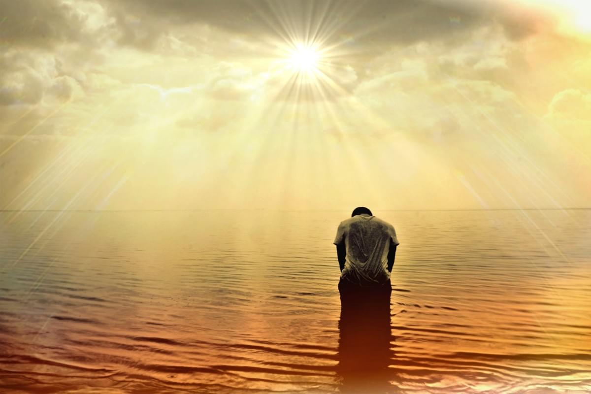 Image of a man standing in the sea, bowed down by his trials, but with the glory of the risen sun in reach of him at last. Image of a man standing in the sea, bowed down by his trials, but with the glory of the risen sun in reach of him at last.