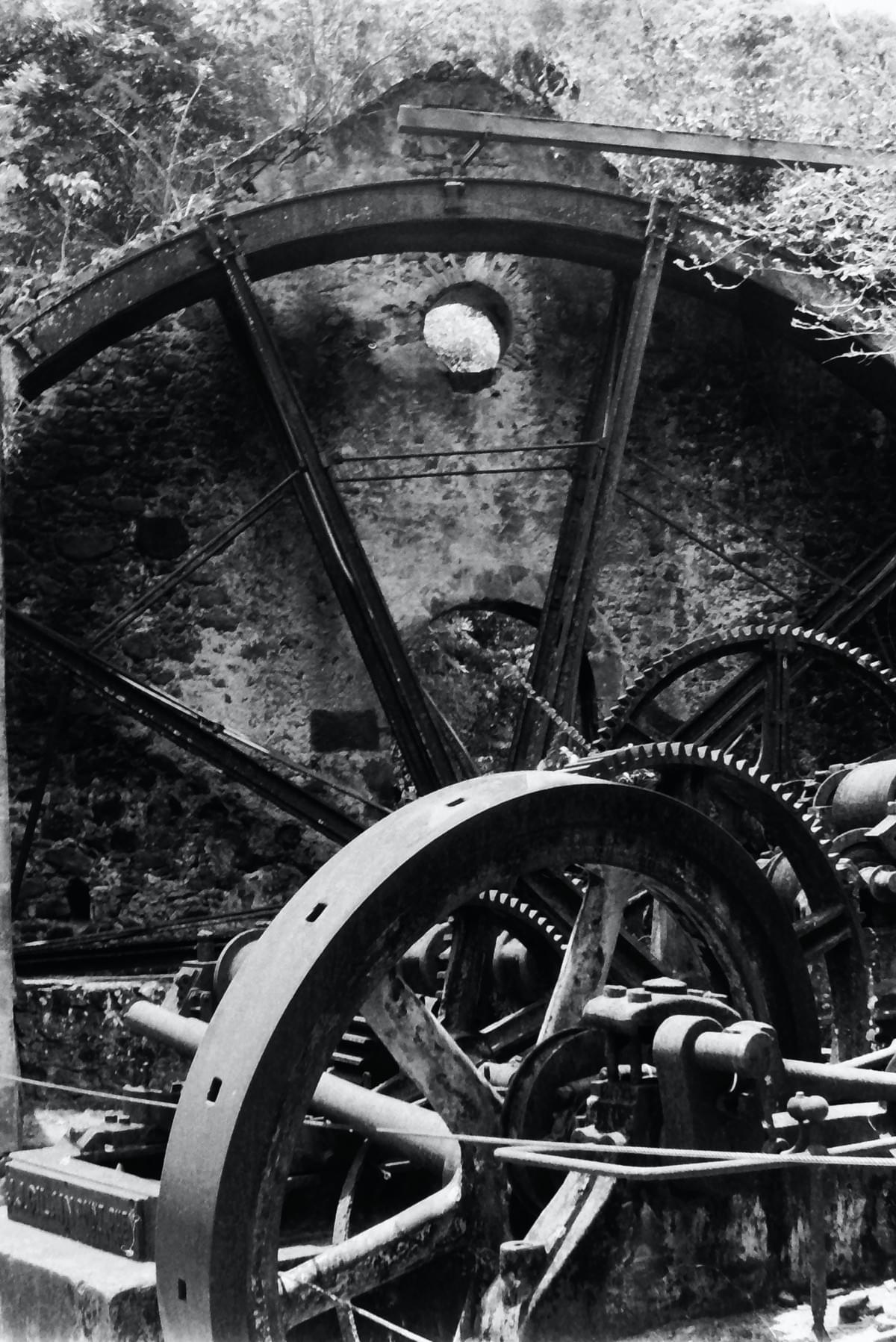 Black and white image by Cade Renfroe of early industrial mill wheels and gearing in a ruined mill. Black and white image by Cade Renfroe of early industrial mill wheels and gearing in a ruined mill.