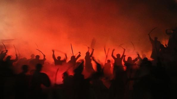Image of fighting, with swords raised. The warriors are silhouetted against a backdrop of red fire. Image of fighting, with swords raised. The warriors are silhouetted against a backdrop of red fire.