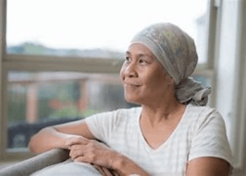 A woman with cancer looks wistfully out a window A woman with cancer looks wistfully out a window