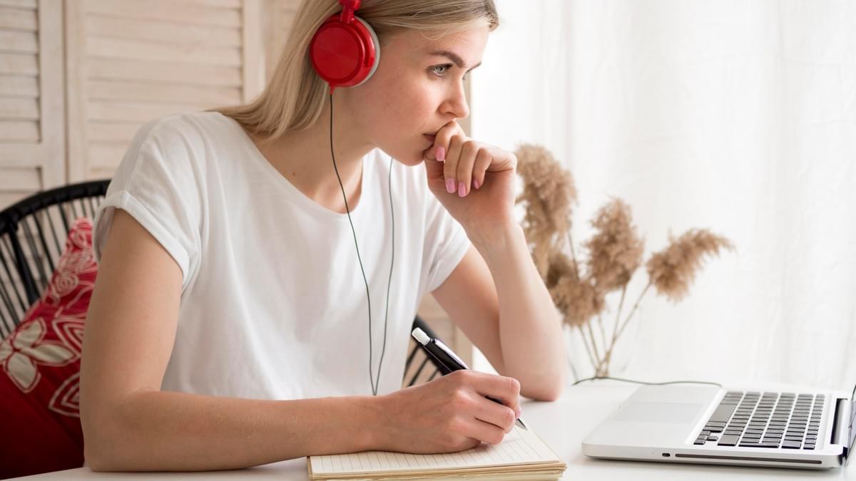 Jeune femme écoutant un cours en ligne et prenant des notes Jeune femme écoutant un cours en ligne et prenant des notes
