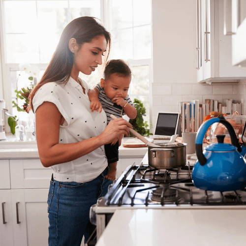 An industrious mom cooks dinner with her baby on her hip. An industrious mom cooks dinner with her baby on her hip.