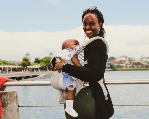 Laura stands on a pier with her youngest child strapped in on her front. Laura stands on a pier with her youngest child strapped in on her front.