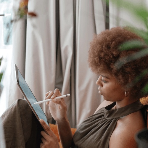 A woman on a couch works diligently on her tablet. A woman on a couch works diligently on her tablet.