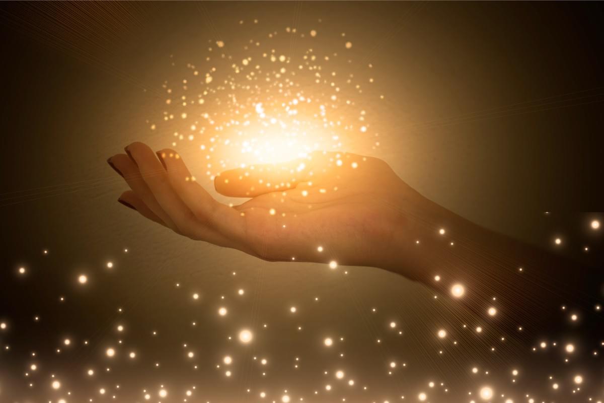 outstretched hand with ball of sparkle and light above outstretched hand with ball of sparkle and light above