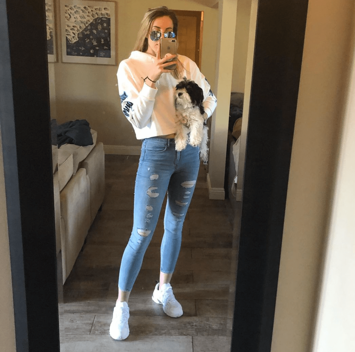Katie Lou holds Malibu (a black and white Morkie) in one arm as she takes photo in mirror with her phone. Katie Lou holds Malibu (a black and white Morkie) in one arm as she takes photo in mirror with her phone.