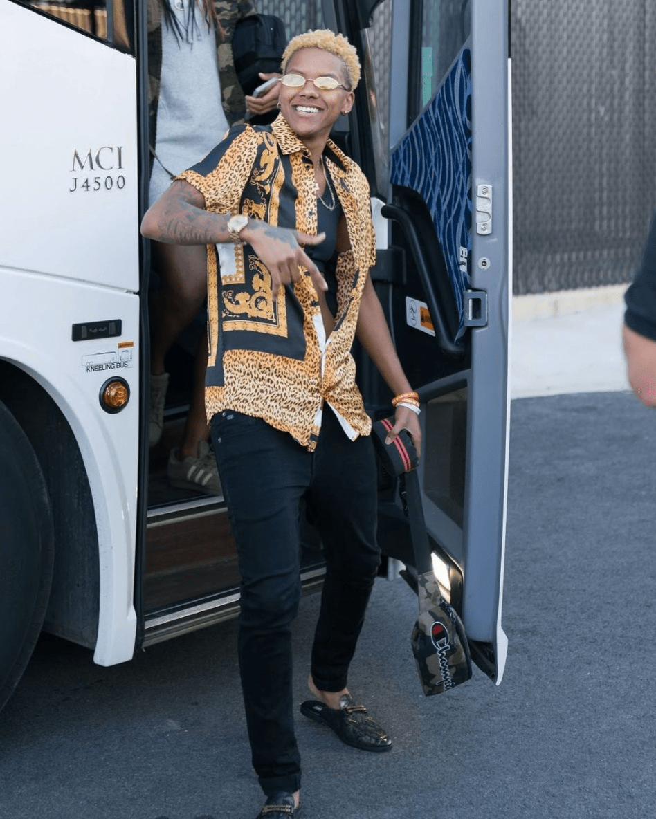 Courtney Williams walks off team bus wearing small sunglasses, leopard, black and gold button up shirt unbuttoned to the waist over black sports bra, black pants, and black patterned flat mules with gold accents. Courtney Williams walks off team bus wearing small sunglasses, leopard, black and gold button up shirt unbuttoned to the waist over black sports bra, black pants, and black patterned flat mules with gold accents.
