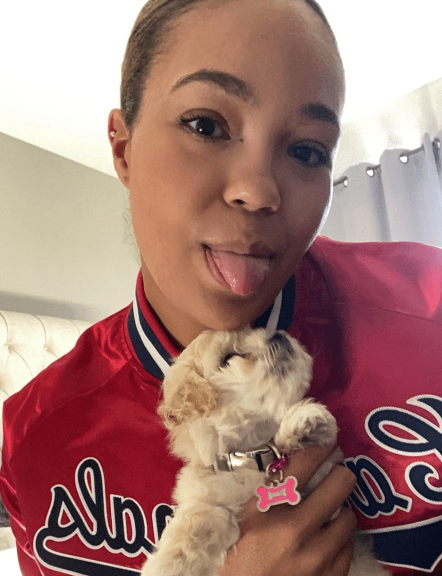Napheesa Collier sticks tongue out while holding very small fluffy white puppy Napheesa Collier sticks tongue out while holding very small fluffy white puppy