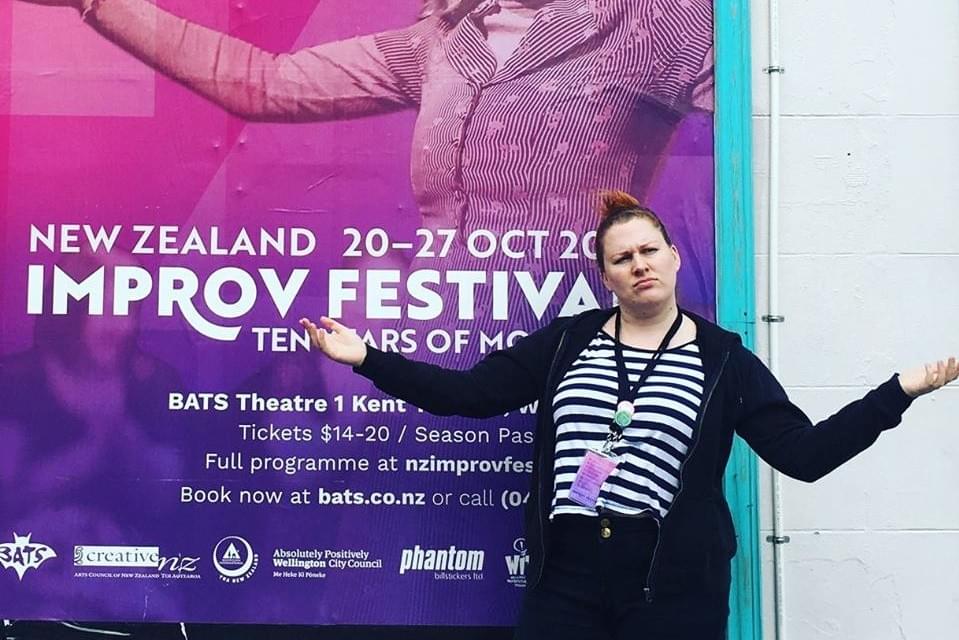 Image: Jennifer posed in front of an NZIF street poster, mirroring the poster’s gesture (arms stretched wide with a sassy face). Photo credit: Abby Howells Image: Jennifer posed in front of an NZIF street poster, mirroring the poster’s gesture (arms stretched wide with a sassy face). Photo credit: Abby Howells