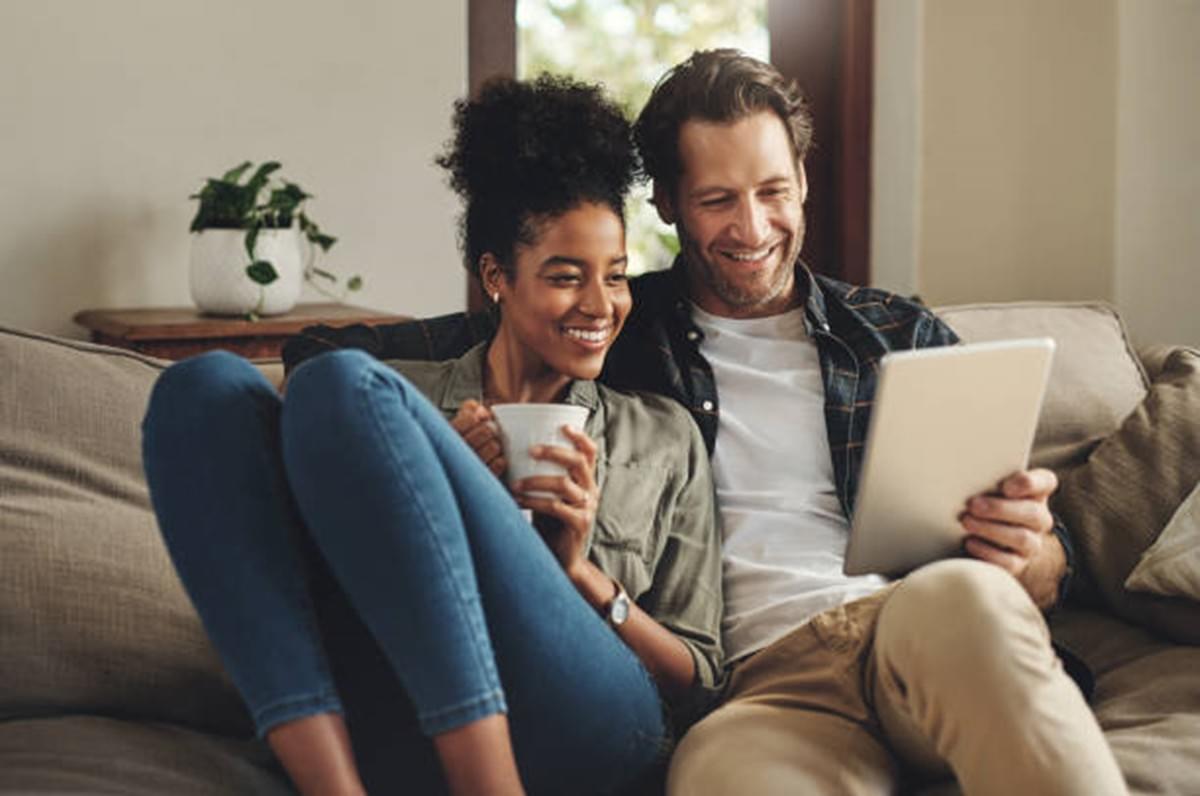 Young couple on a couch looking at a computer tablet Young couple on a couch looking at a computer tablet