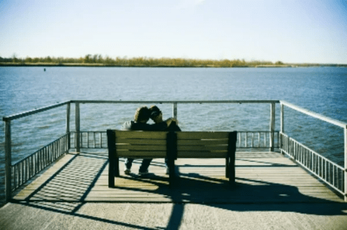 Couple sitting on a bench at a pier Couple sitting on a bench at a pier