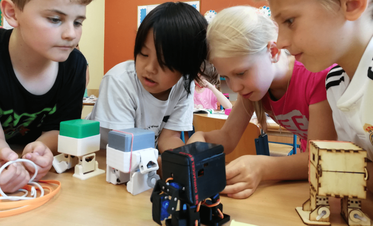4 youngs kids putting together a small robot in a classroom 4 youngs kids putting together a small robot in a classroom