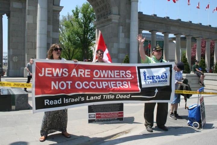 BANNER: 'JEWS ARE OWNERS, NOT OCCUPIERS!' Mark Vandermaas (R) and Joyce Aldrich (L) hold banner and wave to participants of the Walk With Israel near the Canadian National Exhibition in,Toronto. BANNER: 'JEWS ARE OWNERS, NOT OCCUPIERS!' Mark Vandermaas (R) and Joyce Aldrich (L) hold banner and wave to participants of the Walk With Israel near the Canadian National Exhibition in,Toronto.