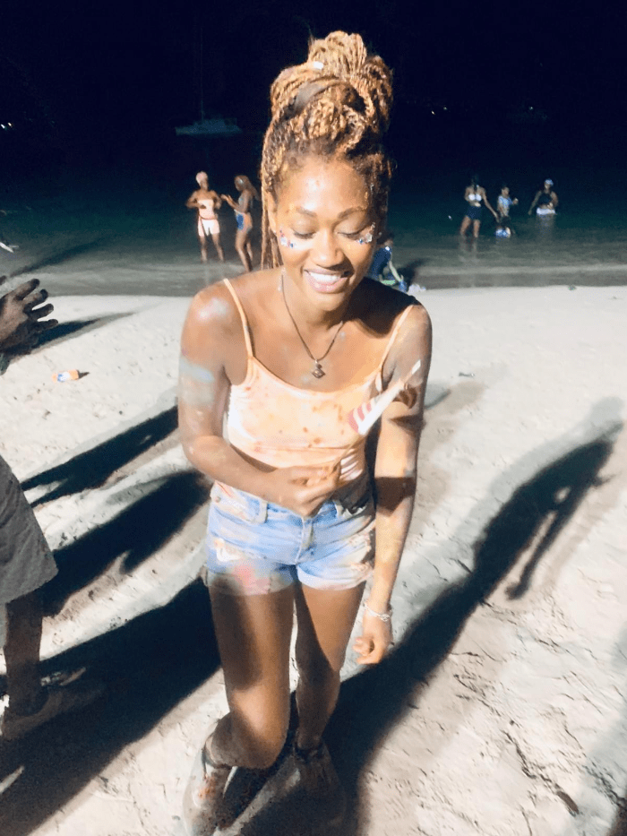 Midnight beach fete in Saint Lucia with a girl smiling covered in party paint powder on the beach Midnight beach fete in Saint Lucia with a girl smiling covered in party paint powder on the beach