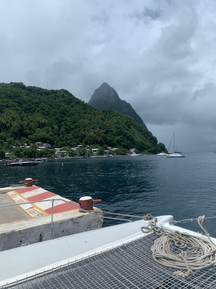 A docked catamaran in front of the Pitons with sailboats and green rainforests and boat rope and netting A docked catamaran in front of the Pitons with sailboats and green rainforests and boat rope and netting