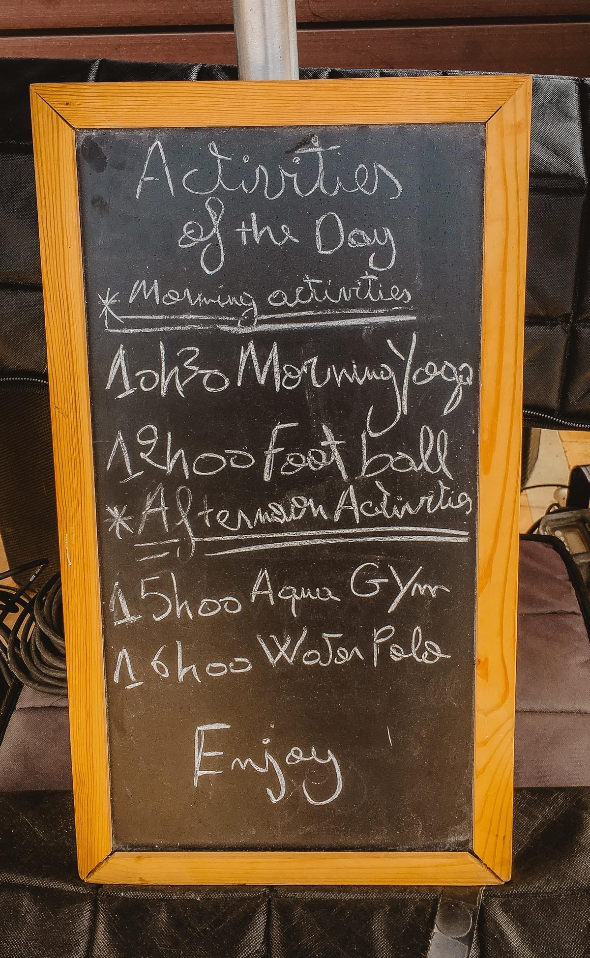 Activities chalkboard with an events calendar reading water polo, football, morning yoga, activities of the day Activities chalkboard with an events calendar reading water polo, football, morning yoga, activities of the day