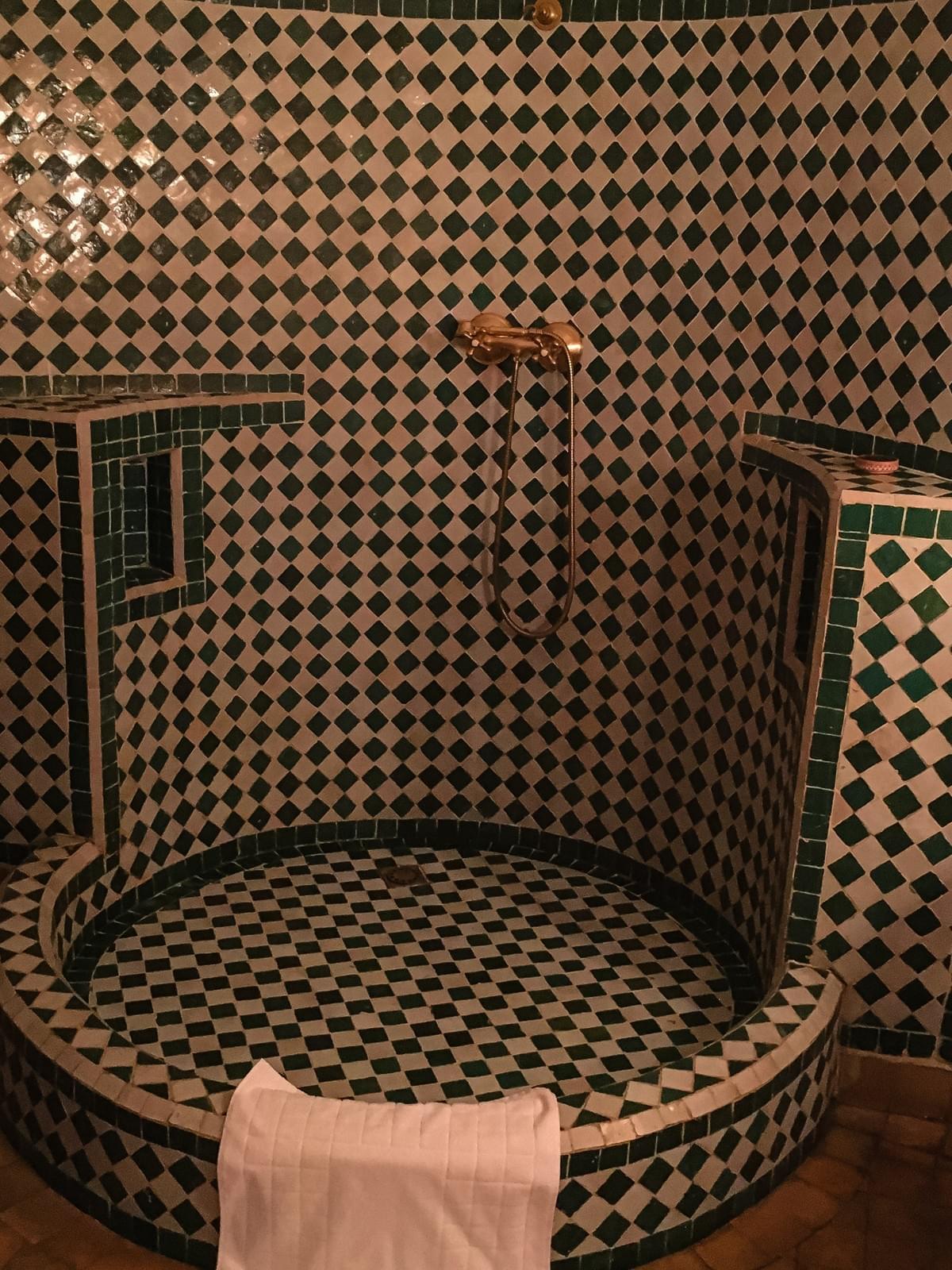 A green and white checkered tiled traditional moroccan bath with a gold faucet A green and white checkered tiled traditional moroccan bath with a gold faucet