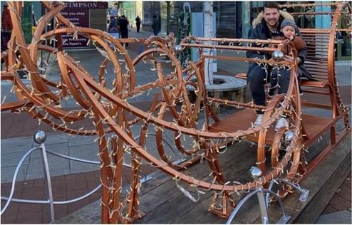 Tom and his son in a reeindeer-shaped sleigh. Tom and his son in a reeindeer-shaped sleigh.