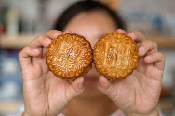 Image showing man holding up mooncakes with Chinese characters imprinted Image showing man holding up mooncakes with Chinese characters imprinted